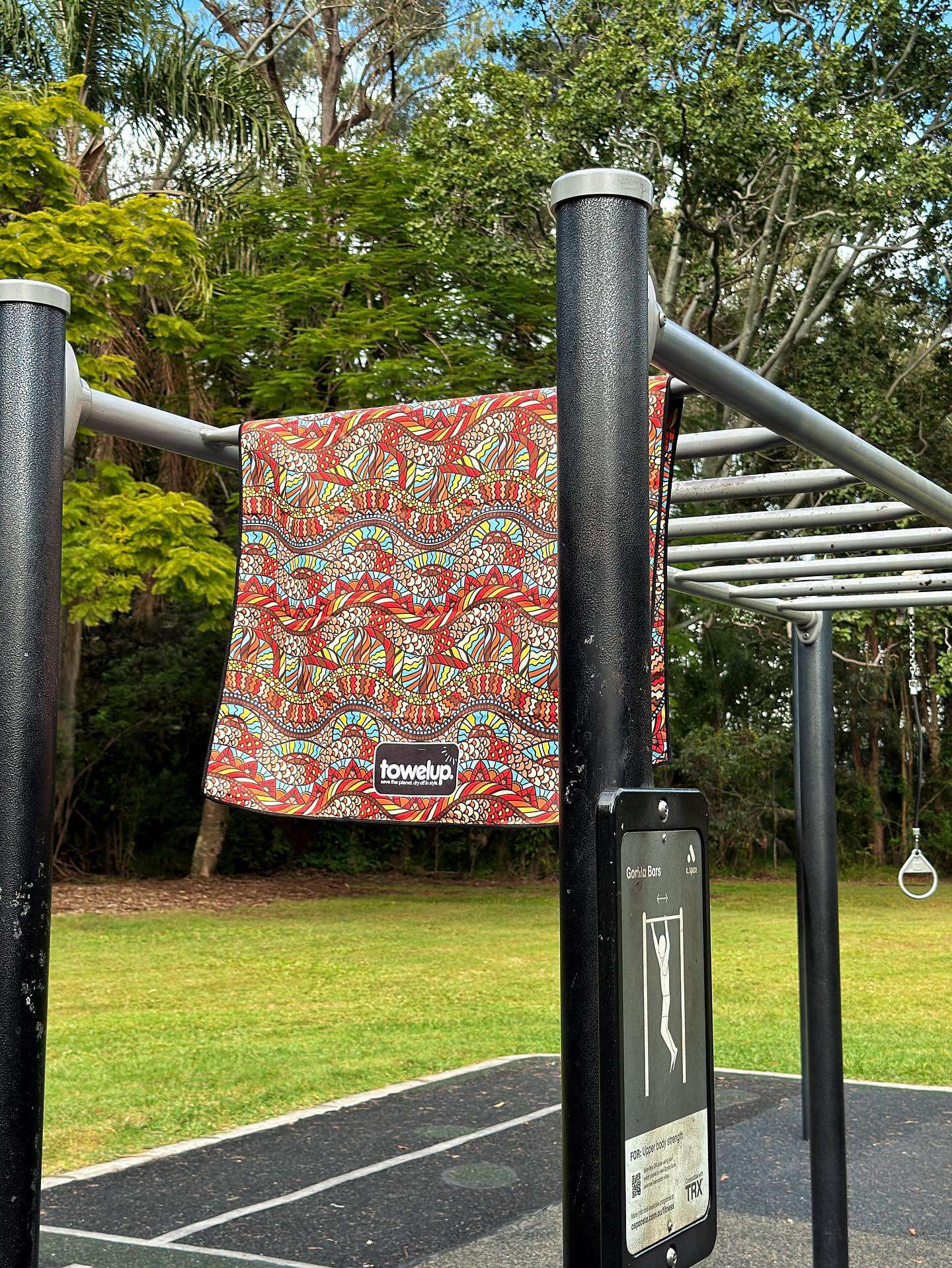 Travel towel from the brand 'towelup.' hanging up in a park outside. Backdrop of nature and trees.