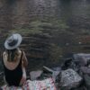 A swimmer sitting on a towel by a lake