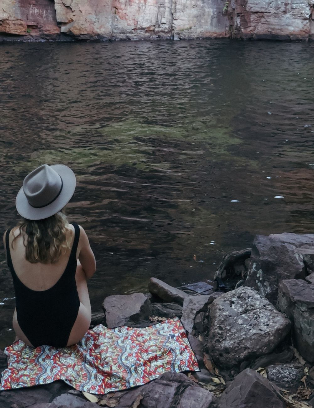 90 A swimmer sitting on a towel by a lake