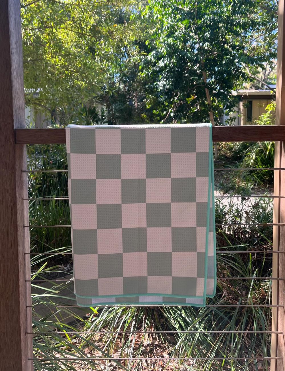 93 A beach towel hanging over a rail in a green scenic backdrop